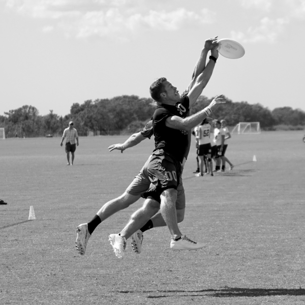 Two atheltes jumping for a disc